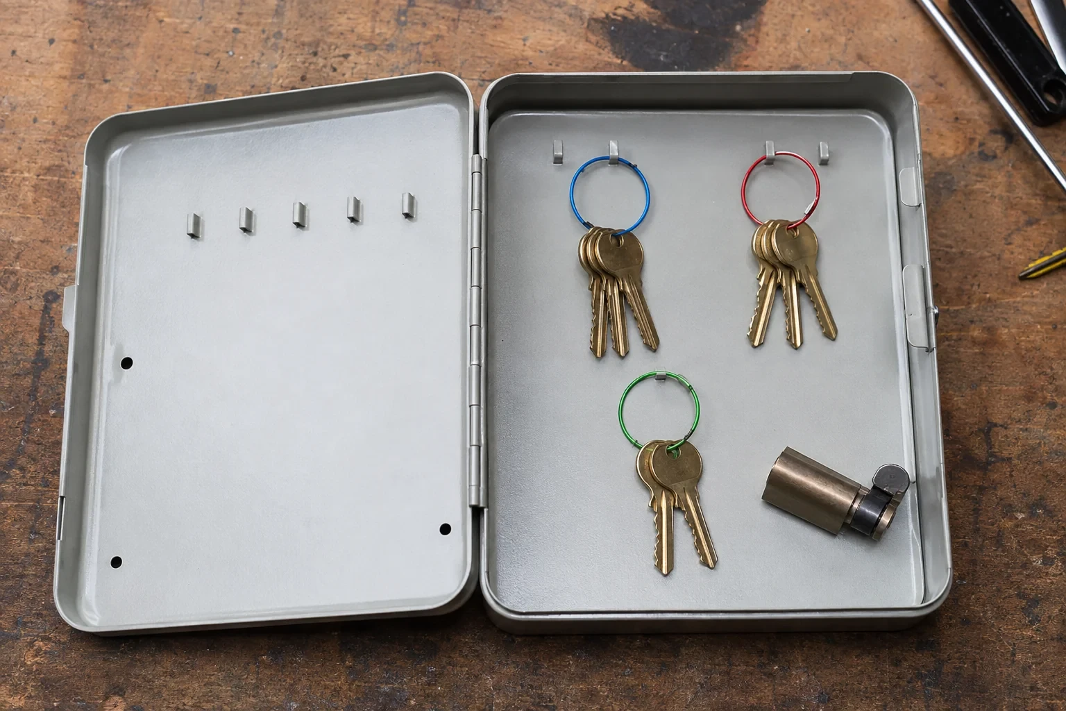 Three groups of keys on colored rings in an open metal key cabinet.